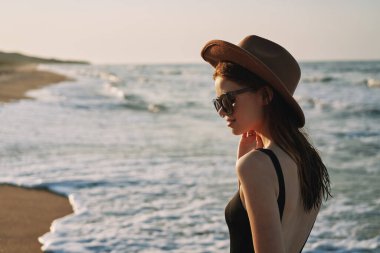 Kumsalda yürüyen bir kadın, tatil güneşinde seyahat ediyor.