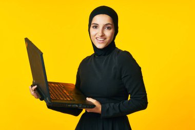 Güzel kadın siyah tesettür dizüstü bilgisayar teknolojisi sarı arka plan