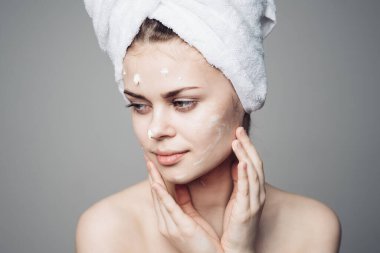 Çıplak omuzlu kadın yüz kremi sürmüş.