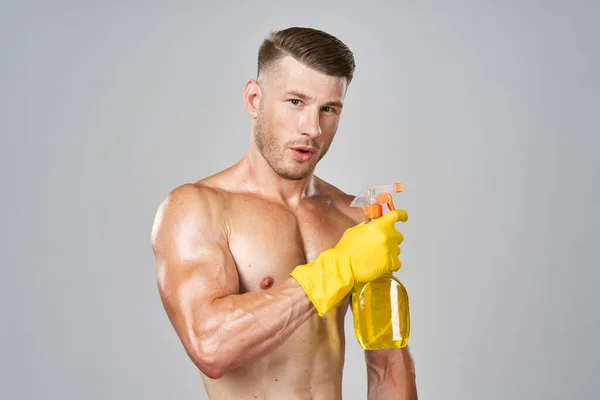 Homem em luvas de borracha amarela com músculos bombeados detergente limpeza — Fotografia de Stock
