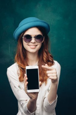 Mavi şapkalı şık bir kadın. Elinde telefon, iletişim teknolojisi var.