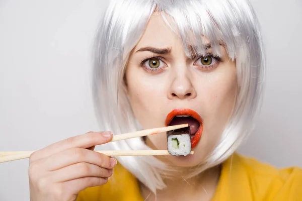 Bonita mujer en peluca blanca y sushi con palillos japoneses — Foto de Stock