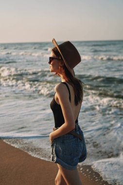 Kumsalda yürüyen bir kadın, tatil güneşinde seyahat ediyor.