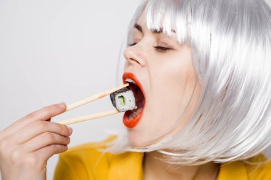 Beyaz peruklu güzel bir kadın ve Japon yemek çubuklarıyla suşi.