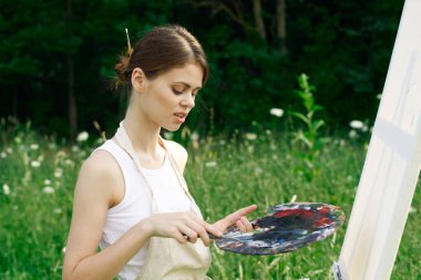 Beyaz elbiseli kadın doğa sanatının resimlerini çiziyor.