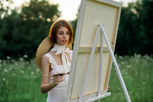 Mujer en vestido blanco pinta una imagen al aire libre hobby creativo — Foto de Stock