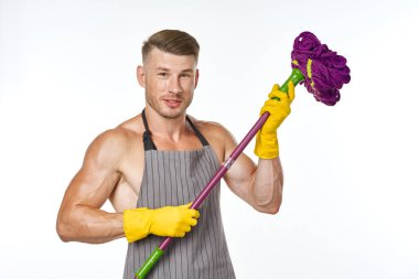 Gri önlüklü, paspas pozu veren kaslı adam.