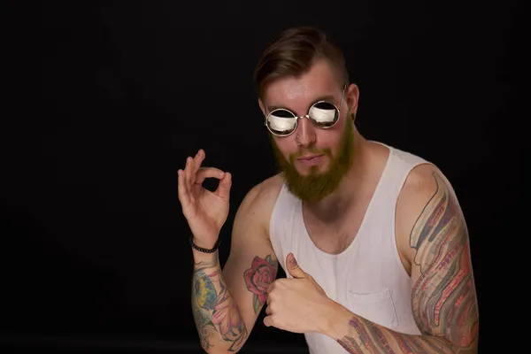 Stilig man med tatueringar på armarna mode solglasögon mörk bakgrund — Stockfoto