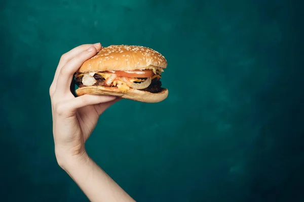 Hamburger w rękach zbliżenie fast food zielone tło — Zdjęcie stockowe