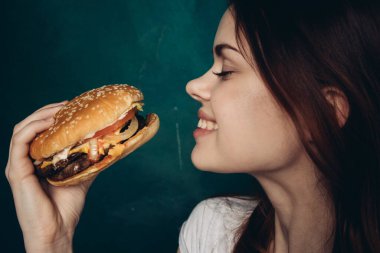 Hamburgerli neşeli kadın fast food yiyor.