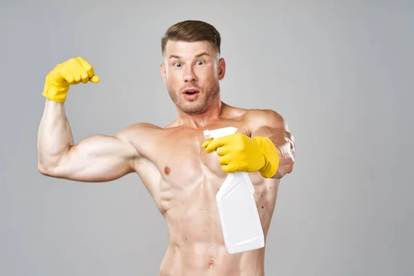 Poz veren şişirilmiş adam lastik eldivenlerle deterjan kullanıyor. — Stok fotoğraf