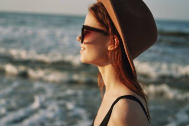 Kumsalda yürüyen bir kadın, tatil güneşinde seyahat ediyor.