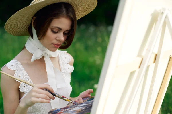 Женщина-художник рисует картину на мольберте на открытом воздухе — стоковое фото