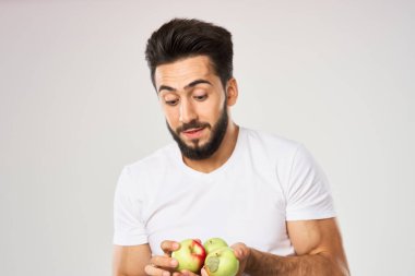Elması beyaz tişörtlü, meyveli neşeli bir adam.