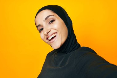 Neşeli kadın etnik köken modeli duygularını sarı arka planda gösteriyor.