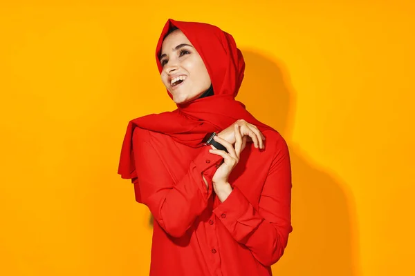 Mujer en rojo hijab reloj electrónico tecnología de entretenimiento fondo amarillo —  Fotos de Stock