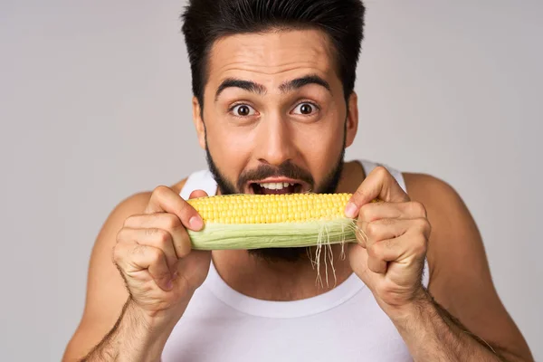 Beyaz tişörtlü bir adam elinde mısır taze sebzeler stüdyoda yaşam tarzı — Stok fotoğraf