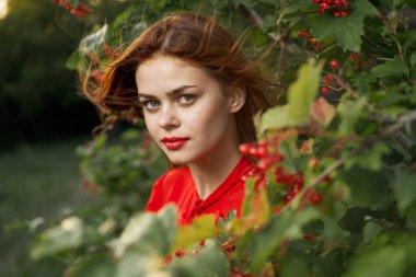 Kırmızı tişörtlü güzel kadın yeşil yapraklı yaz.