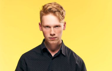 Siyah tişörtlü kızıl saçlı adam modern poz veriyor.