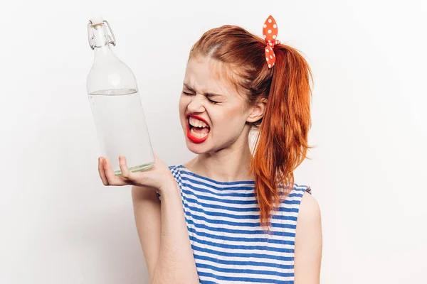 Vacker kvinna i randig t-shirt med flaska alkohol ljus bakgrund — Stockfoto