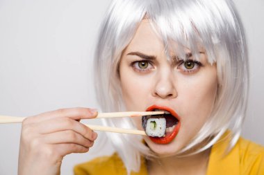 Beyaz peruklu güzel bir kadın ve Japon yemek çubuklarıyla suşi.
