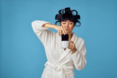 Beyaz önlüklü ev hanımı, mavi arka planı temizliyor.