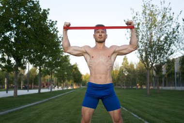 Parktaki spor salonunda mavi şortlu bir adam.