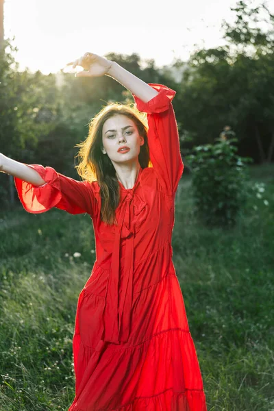 Attraente donna in abito rosso in posa in natura erba verde — Foto Stock