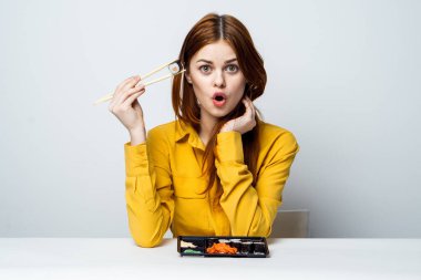 Masada suşi yiyen bir kadın Japon atıştırmalığı yiyor.
