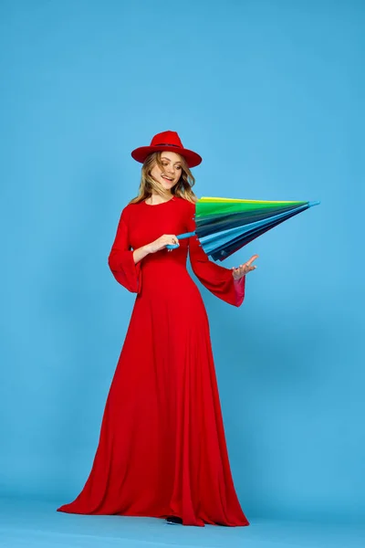 붉은 옷을 입은 여자, 다양 한 색깔의 우산 파란색 배경 — 스톡 사진