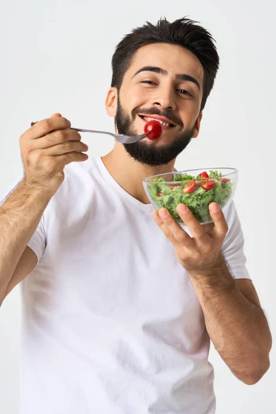 Vrolijke man in een wit T-shirt met een bord lichtgroen en een gezonde maaltijd — Stockfoto