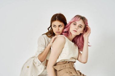 İki kız arkadaş yan yana durmuş, moda zevkini sergiliyorlar.