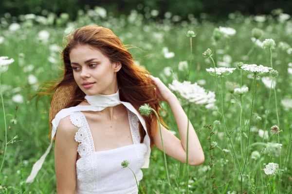 Vacker kvinna i vit klänning och hatt poserar blommor natur — Stockfoto