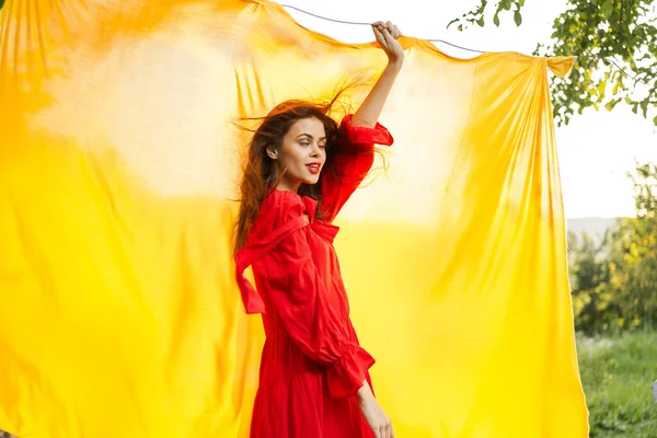 Kırmızı elbiseli neşeli bir kadın elleriyle işaret ediyor.