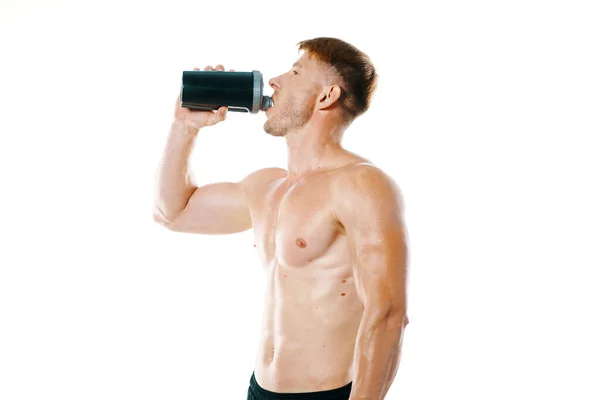 Чоловік спортсмен з перекачаним тілом п'є з пляшки — стокове фото