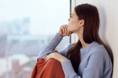 Pencere kenarında oturan kadın ekoseli bir sabah hayatı yaşıyor.