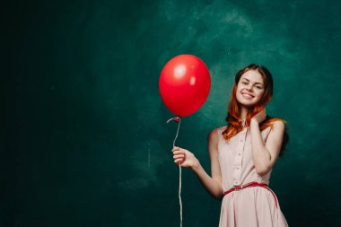 Kırmızı balonlu neşeli kadın yeşil arka plan tatili