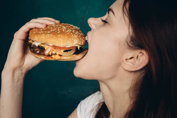 Mujer alegre con hamburguesa cerca de la cara snacking comida rápida —  Fotos de Stock