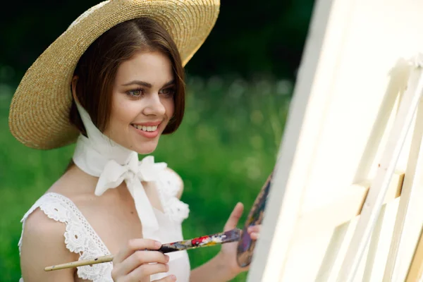 Artista mulher em chapéu com pincel pinta um quadro — Fotografia de Stock