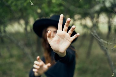 Siyah şapkalı bir kadın elleriyle bir cadı fantezisi kuruyor.