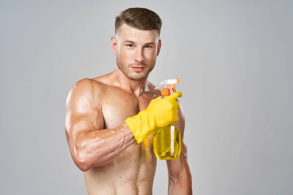 头戴黄色橡胶手套，肌肉抽吸洗涤剂清洗的男人 — 图库照片