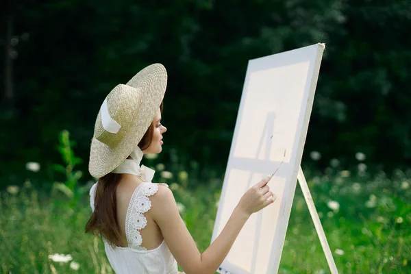 Mujer vestida de blanco en la naturaleza pinta un cuadro de un hobby paisajístico —  Fotos de Stock