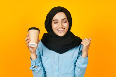 Stüdyo yaşam tarzı pozu veren sıcak bir içecek içen güzel bir kadın.