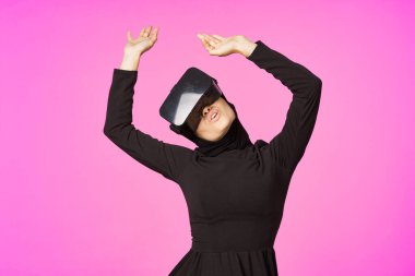 Siyah tesettürlü kadın gözlüklü sanal gerçeklik teknolojisi filmi izliyor