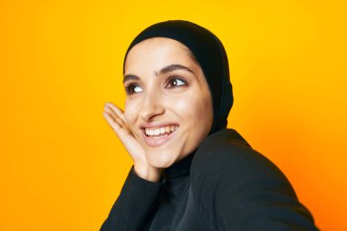 Arap kadını eğlenceli etnik köken modeli duygularını sarı arka planda gösteriyor.