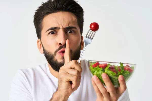 Homme gai dans un t-shirt blanc une assiette avec salade légumes régime — Photo