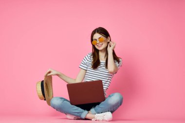 Pembe arka planda dizüstü bilgisayarı olan neşeli bir kadın.