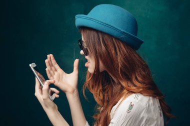 Mavi şapkalı şık bir kadın. Elinde telefon, iletişim teknolojisi var.
