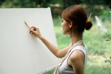 Kadın açık havada yaratıcı bir resim çiziyor.