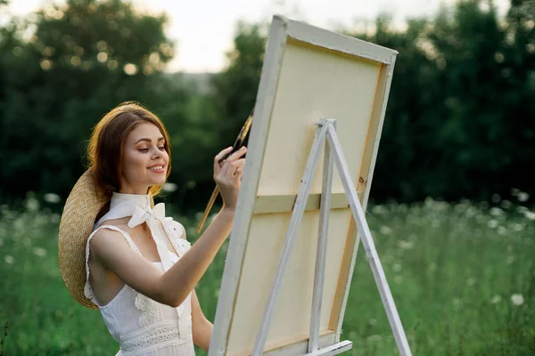 Kobieta w białej sukience maluje obraz na świeżym powietrzu hobby kreatywne — Zdjęcie stockowe